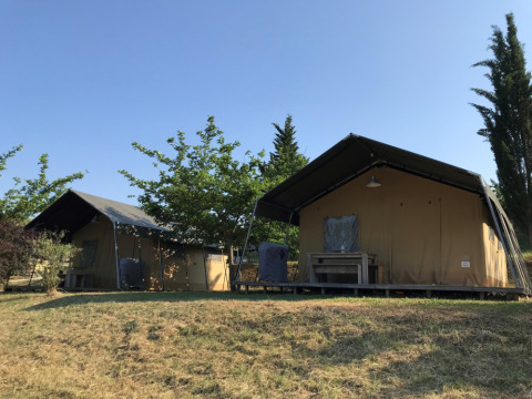 Two tents at Camping Podere sei Poorte, a holiday park in Marche, Italy, surrounded by greenery and trees.