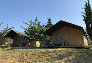 Two tents at Camping Podere sei Poorte, a holiday park in Marche, Italy, surrounded by greenery and trees.