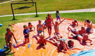 Bambini che giocano su uno scivolo d'acqua arancione a Camping Podere sei Poorte nelle Marche, Italia.