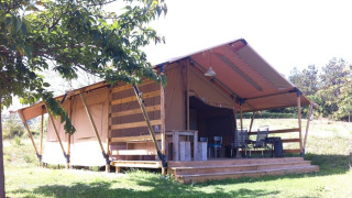 Safari tent with sanitary facilities at Camping Podere Sei Poorte in Italy, wooden deck and chairs visible.