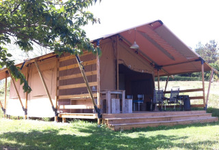 Large safari tent with wooden deck at Camping Podere sei Poorte holiday park in Marche, Italy, in sunlight.