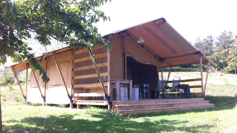Large safari tent with wooden deck at Camping Podere sei Poorte holiday park in Marche, Italy, in sunlight.