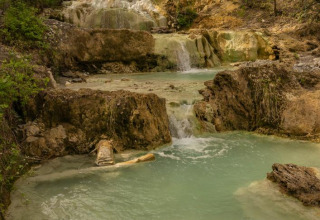 Kleine waterval en helderblauwe poelen omringd door groen nabij Monteciccardo in de regio Marche, Italië.