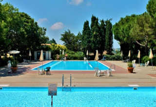 Udendørs swimmingpool omgivet af stole og parasoller på Camping Mar y Sierra i Marche, Italien, om sommeren.