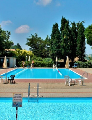Piscine extérieure avec chaises et parasols au Camping Mar y Sierra, parc de vacances à Marche, Italie.