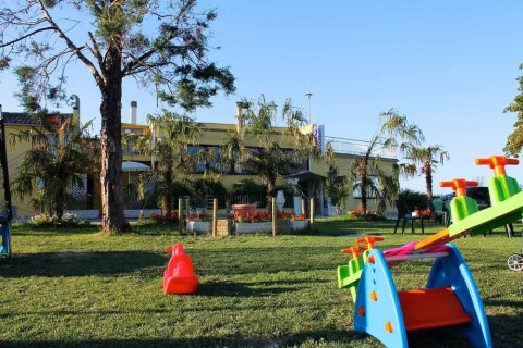 Area giochi con attrezzature colorate e prato davanti agli alloggi di Camping Mar y Sierra nelle Marche, Italia.