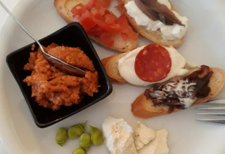 Piatto di antipasti con bruschette assortite, formaggio, fave e salsa, servito in un campeggio italiano.