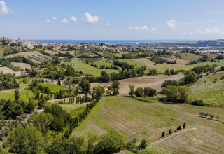 Vista panorámica desde Camping Mar y Sierra en Marche, Italia, con colinas verdes y un pueblo lejano.