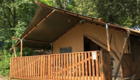 Tienda tipo safari con terraza de madera en Camping Mar y Sierra, rodeada de árboles en Marche, Italia, verano.