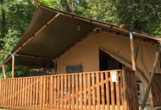 Tenda safari con veranda in legno nel verde a Camping Mar y Sierra, nelle Marche, Italia, durante l’estate.