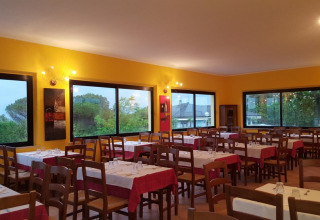 Intérieur de restaurant au Camping Mar y Sierra, Marche, Italie, avec chaises en bois et grandes fenêtres.