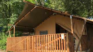Tenda safari con veranda e servizi igienici privati al Camping Mar y Sierra in Italia, tra gli alberi.