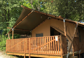 Safari-Zelt mit Sanitäranlagen auf Camping Mar y Sierra in Italien, umgeben von grünen Bäumen.