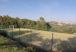 Udsigt over en fodboldbane med hegn, omgivet af natur, på Camping Mar y Sierra i Marche, Italien.