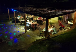 Sera al Camping Paradiso nelle Marche, Italia, con ospiti che cenano sotto una terrazza coperta.