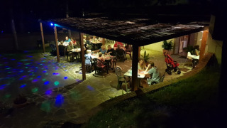 Sera al Camping Paradiso nelle Marche, Italia, con ospiti che cenano sotto una terrazza coperta.