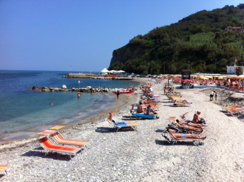 Bañistas disfrutan bajo el sol en tumbonas coloridas en la playa de Camping Paradiso, en Marche, Italia.