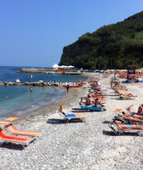 Turisti prendono il sole su lettini colorati sulla spiaggia di ciottoli vicino al Camping Paradiso, Marche.