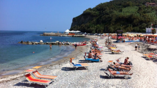 Turisti prendono il sole su lettini colorati sulla spiaggia di ciottoli vicino al Camping Paradiso, Marche.