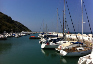 Sejlbåde og lystbåde fortøjet i en rolig havn nær Pesaro, Marche, Italien, på en solrig dag med blå himmel.