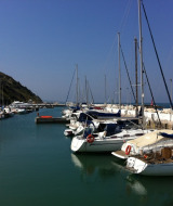 Barche a vela e yacht ormeggiati in un porto tranquillo vicino a Pesaro, Marche, Italia, in una giornata di sole.
