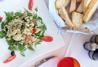 Cibo su un tavolo con pane, insalata e pomodori, foto scattata al Camping Paradiso, Marche, Italia.