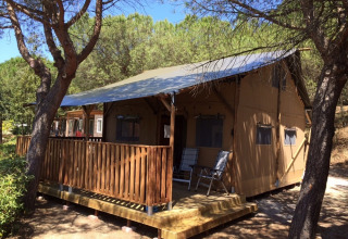 Tenda safari con servizi igienici al Camping Paradiso in Italia, circondata da alberi e vegetazione.