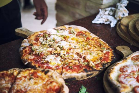 Freshly baked pizza served on a wooden board, a highlight of Camping Paradiso holiday park in Marche, Italy.