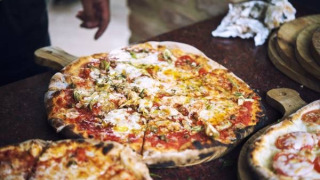 Pizza appena sfornata su tagliere di legno, una delle specialità di Camping Paradiso nelle Marche, Italia.