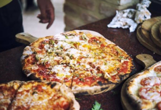 Freshly baked pizza served on a wooden board, a highlight of Camping Paradiso holiday park in Marche, Italy.
