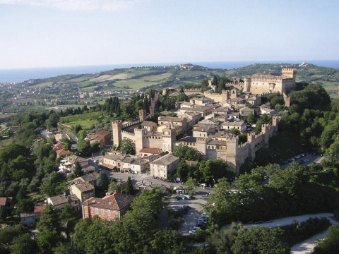 Veduta aerea di un borgo medievale fortificato vicino a Pesaro, Marche, Italia, circondato da colline verdi.