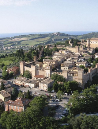 Veduta aerea di un borgo medievale fortificato vicino a Pesaro, Marche, Italia, circondato da colline verdi.
