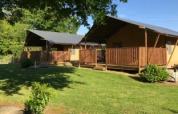 Two cozy safari tents with wooden decks at Camping de Kerleyou holiday park in Brittany, France, surrounded by greenery.