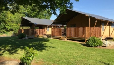 Two cozy safari tents with wooden decks at Camping de Kerleyou holiday park in Brittany, France, surrounded by greenery.