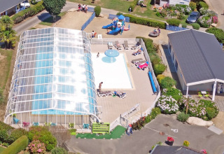 Luftfoto af Camping de Kerleyou i Bretagne, Frankrig, med overdækket pool, børneområde og ferieboliger.