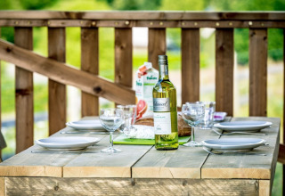 Tavolo all'aperto apparecchiato con vino e bicchieri al Camping de Kerleyou in Bretagna, Francia.