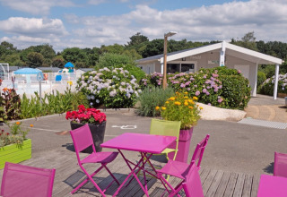 Udendørsområde med farverige borde, blomster og pool på Camping de Kerleyou i Bretagne, Frankrig.