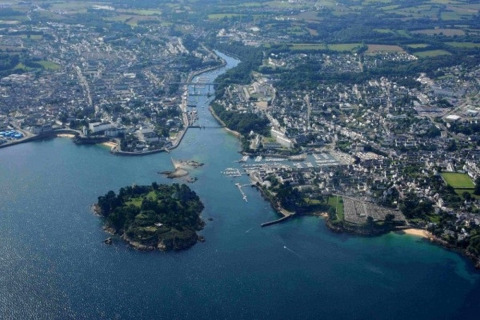 Foto aérea de Douarnenez en Bretaña, Francia, mostrando la costa, el paisaje urbano y una isla cercana.