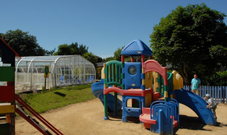 Plastic playground at Camping de Kerleyou holiday park in Brittany, France, with children playing outside.