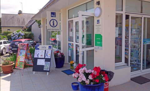 Recepción de Camping de Kerleyou en Bretaña, Francia, con flores, carteles de información y coches aparcados.