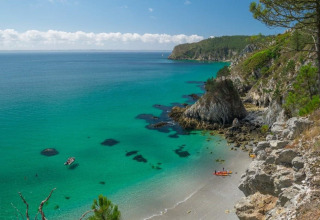 Smuk udsigt over turkisblåt hav, klipper og strand ved Camping de Kerleyou, feriested i Bretagne, Frankrig.