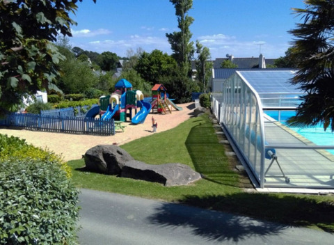 Parque infantil y piscina cubierta en Camping de Kerleyou, un parque vacacional en Bretaña, Francia, al sol.
