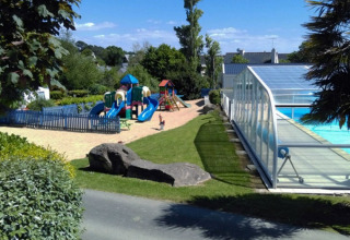 Legeland og overdækket swimmingpool ved Camping de Kerleyou, en feriepark i Bretagne, Frankrig, på en solrig dag.