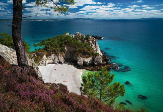 Scenic view of a rocky cove with turquoise water and white sand beach near Douarnenez, Brittany, France.