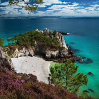 Scenic view of a rocky cove with turquoise water and white sand beach near Douarnenez, Brittany, France.