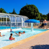 Children playing in the pool at Camping de Kerleyou, sunny holiday park scene in Brittany, France.