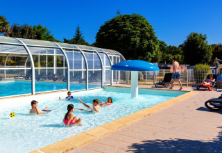 Bambini che giocano in piscina al Camping de Kerleyou, giornata di sole in villaggio vacanze in Bretagna, Francia.