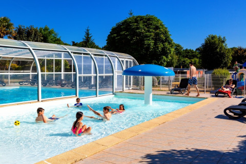 Børn leger i swimmingpool ved Camping de Kerleyou, solrig dag, feriested i Bretagne, Frankrig.