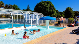 Children playing in the pool at Camping de Kerleyou, sunny holiday park scene in Brittany, France.