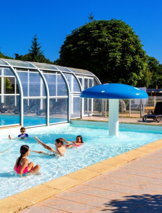 Children playing in the pool at Camping de Kerleyou, sunny holiday park scene in Brittany, France.